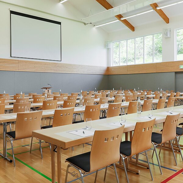 Helle Mehrzweckhalle mit Tisch- und Sitzreihen