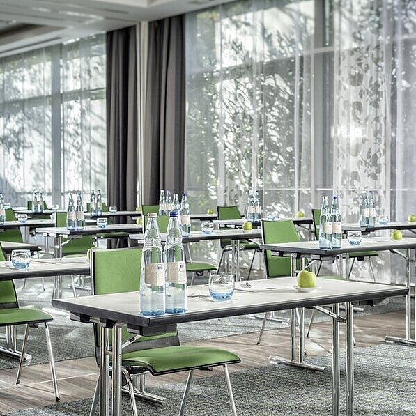 Tagungsraum im Hotel in Neuss mit Einzeltischen und grünen Stühlen 