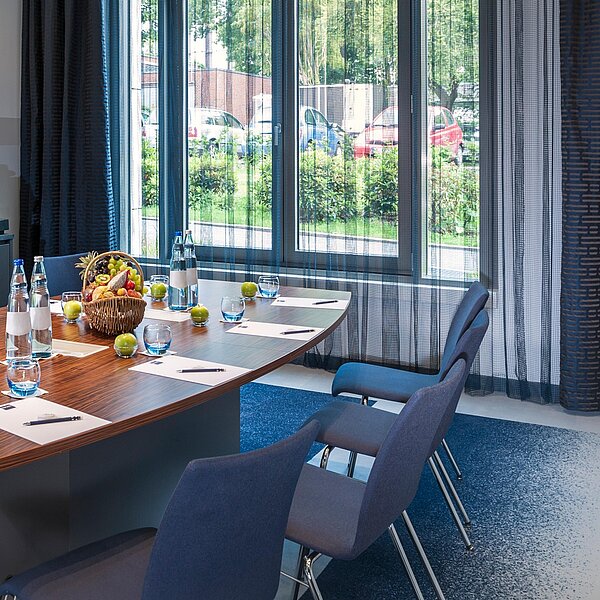 Boardroom mit Gruppentisch, Obst und heller Fensterfront im Hintergrund