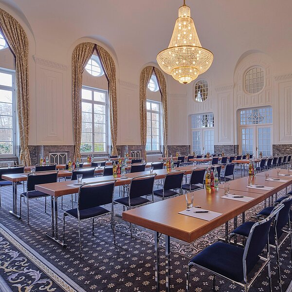 Historischer Tagungsraum mit riesigen Fenstern und hohen Decken, Kronleuchter und Tischreihen
