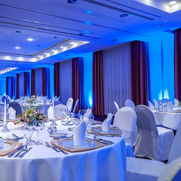 Gedecktes Dinner im Festsaal an runden Tisch mit blauer Hintergrundbeleuchtung