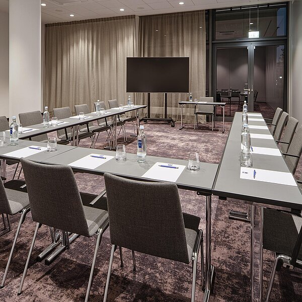 Moderner Meetingraum in U-Bestuhlung und lila Teppichboden