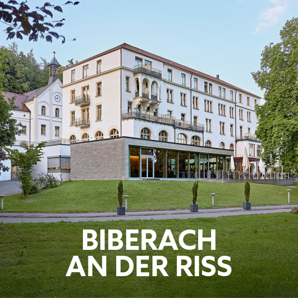 Light-colored house facade with green meadows in front of it