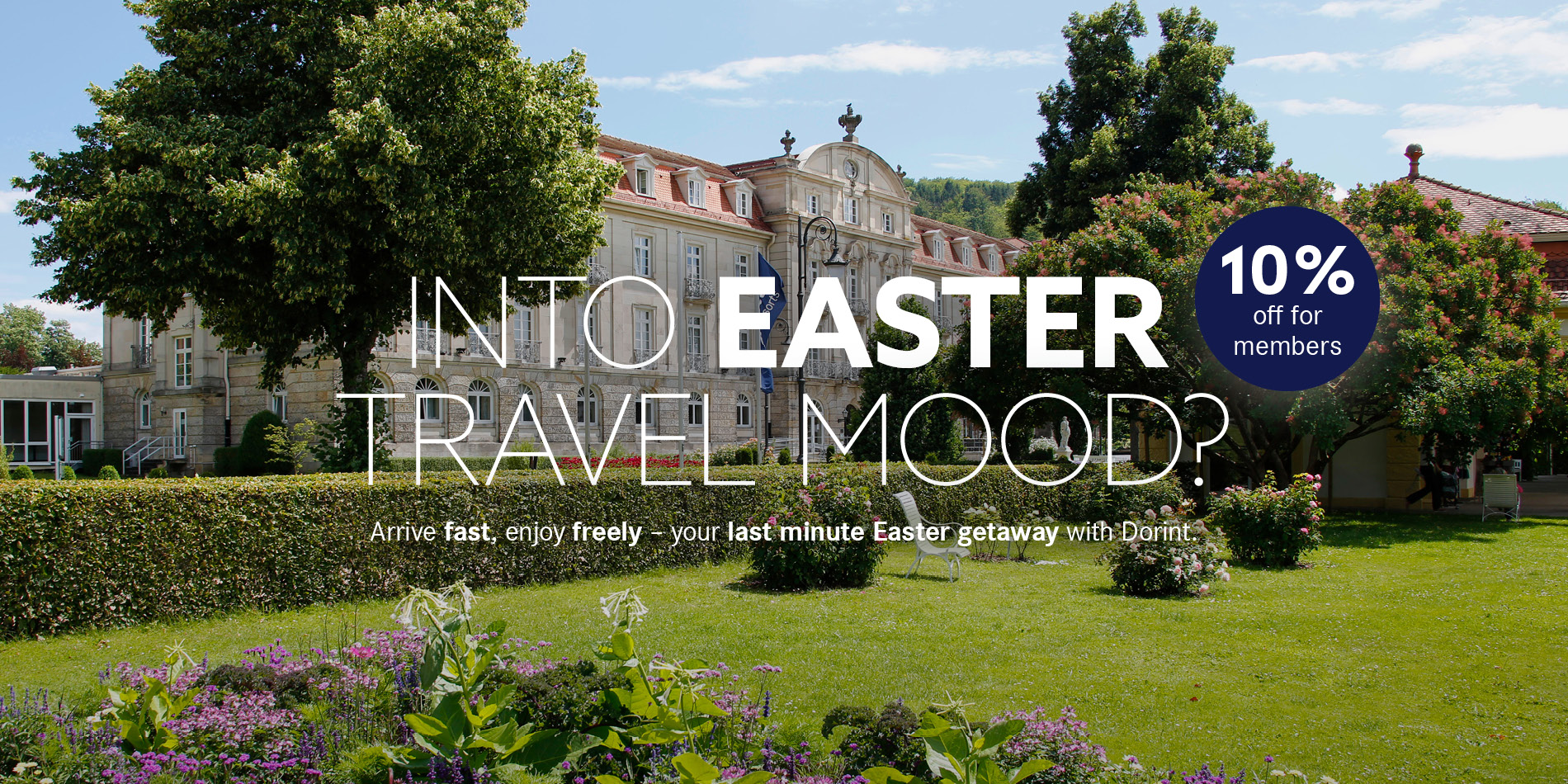 Facade of the Dorint Hotel Bad Brückenau, with a green meadow and plants in the foreground and signage already in an Easter travel mood
