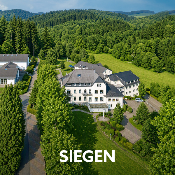 Luftaufnahme des Dorint Parkhotels Siegen, umgeben von Wäldern und grüner Parklandschaft. Text im Bild: „Siegen“.