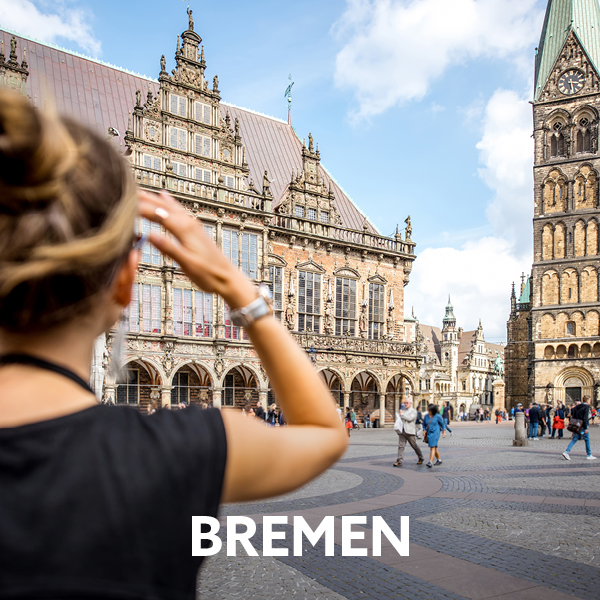 Das Bild zeigt eine Touristin, die den Marktplatz von Bremen mit dem Rathaus und dem Dom bewundert.