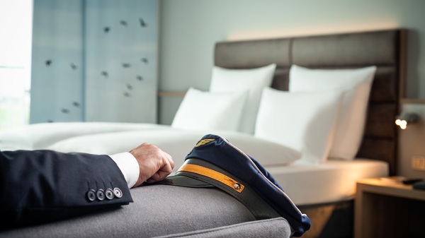 Modernes Hotelzimmer im Essential by Dorint Stuttgart/Airport mit Pilotenmütze im Vordergrund und Doppelbett im Hintergrund