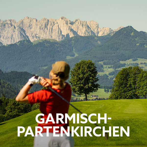 Blick auf die Zugspitze. Davor Grün und Golferin mit rotem T-Shirt beim Abschlag ihres Golfballs. Schriftzug Garmisch-Partenkirchen